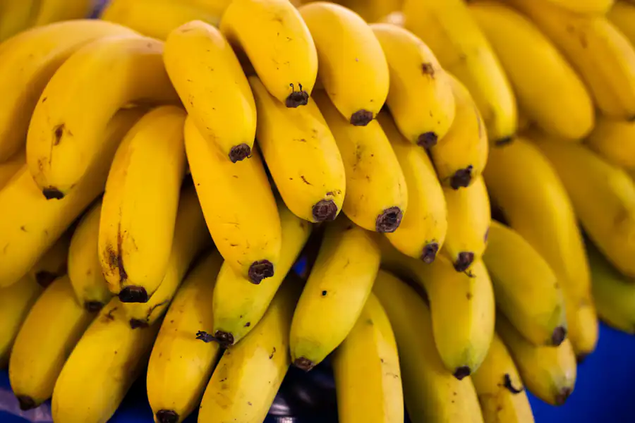 Cachos de banana madura empilhados em banca