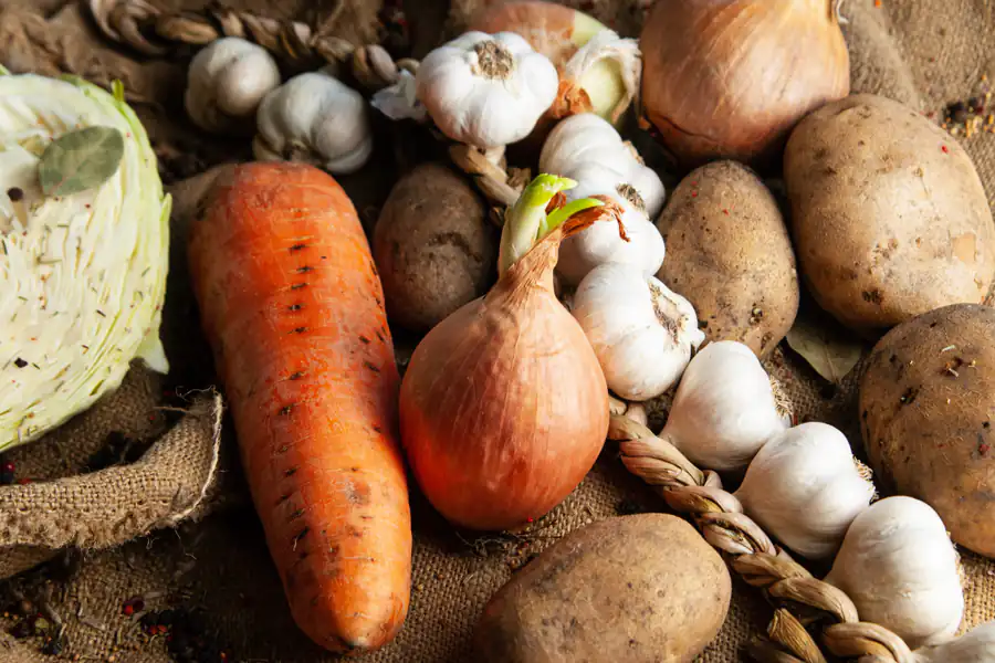 Cenoura, batata, cebola e alho sobre pano de estopa